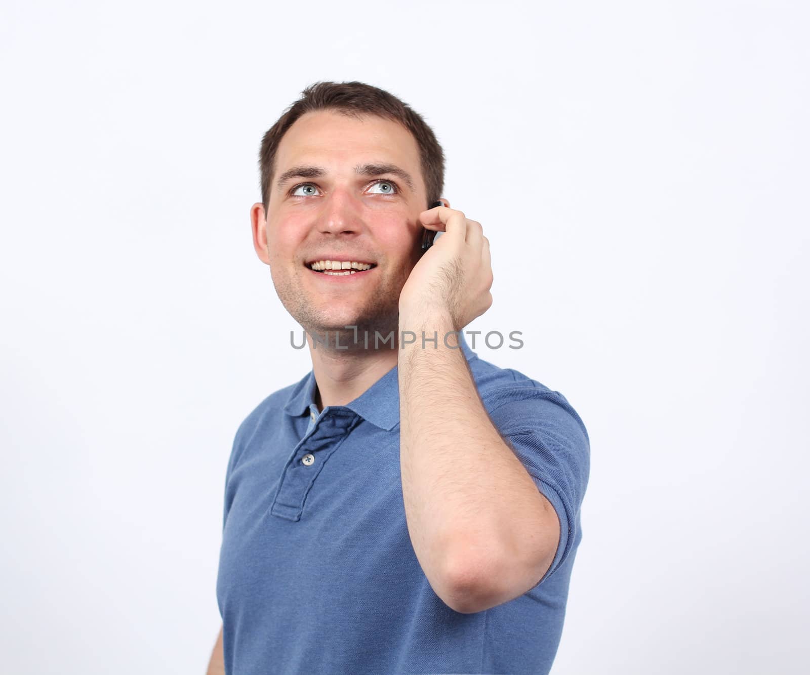 Smiling young man on his mobile phone against a white background