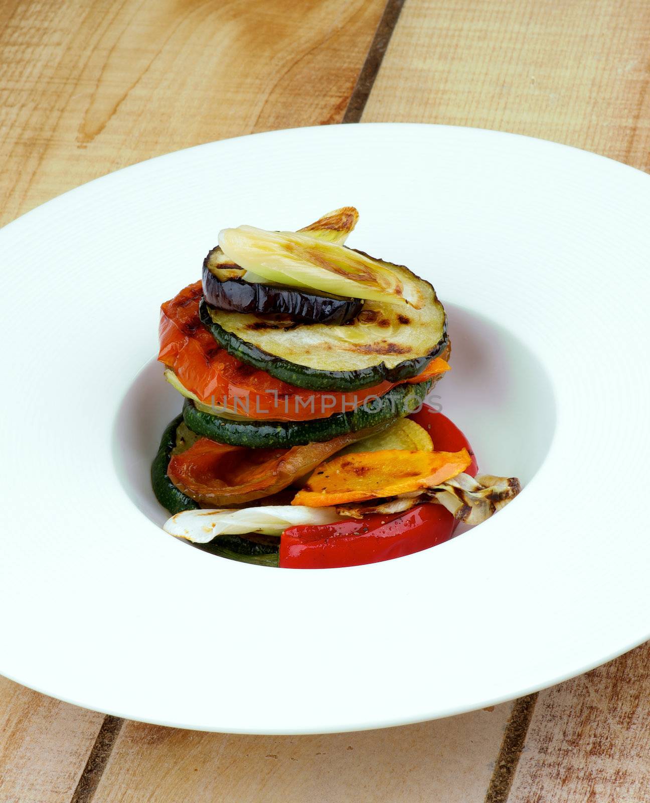 Delicious Traditional Ratatouille with Grilled Vegetables and Spices in White Plate closeup on Wooden Table background