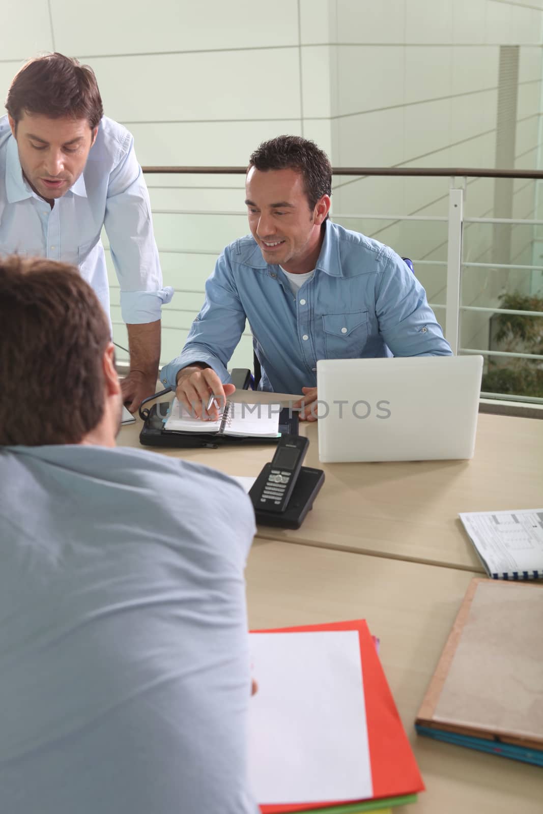 Three male colleagues at work by phovoir
