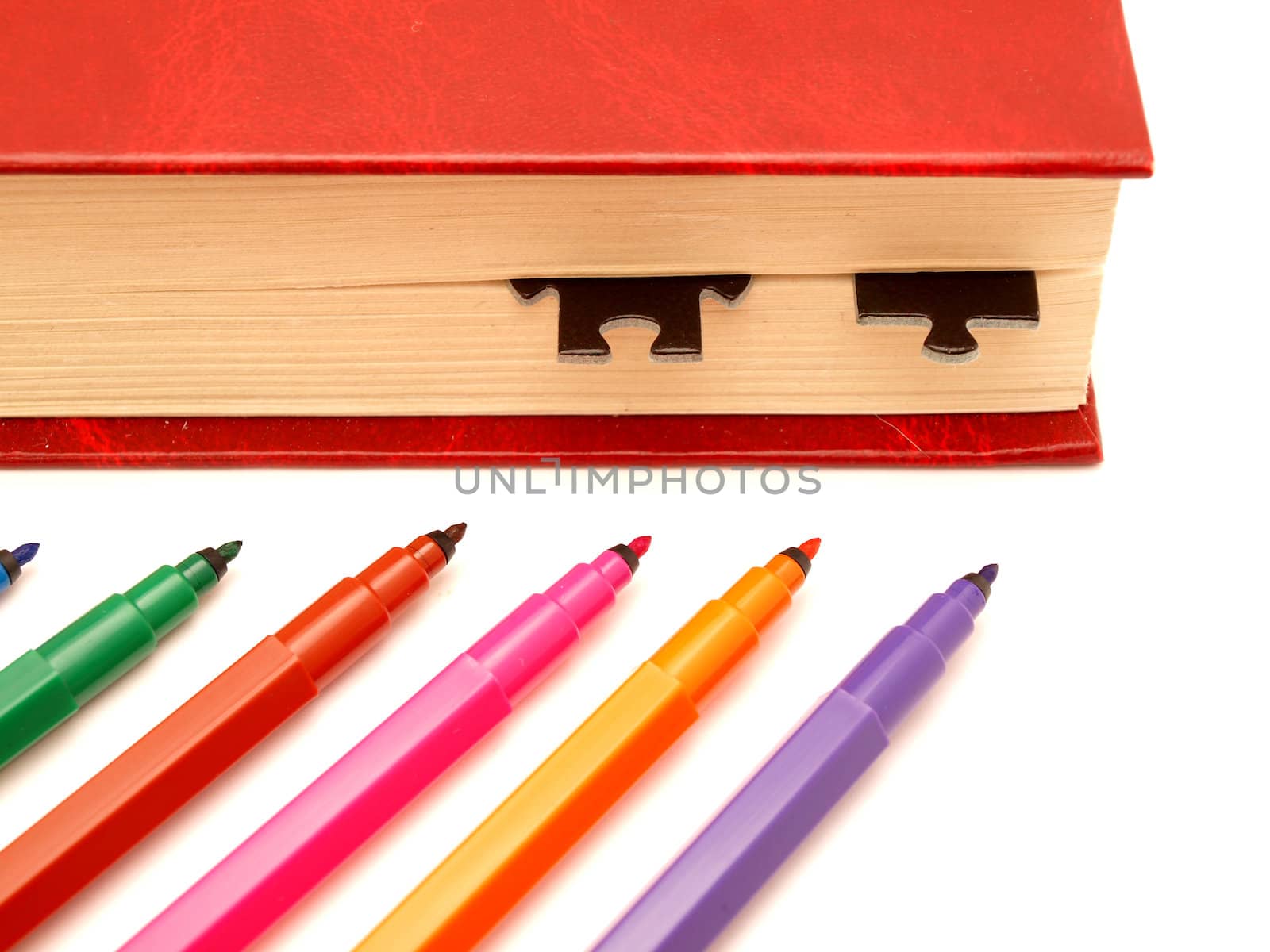 Color felt-tip pens, book and puzzle on a white background        