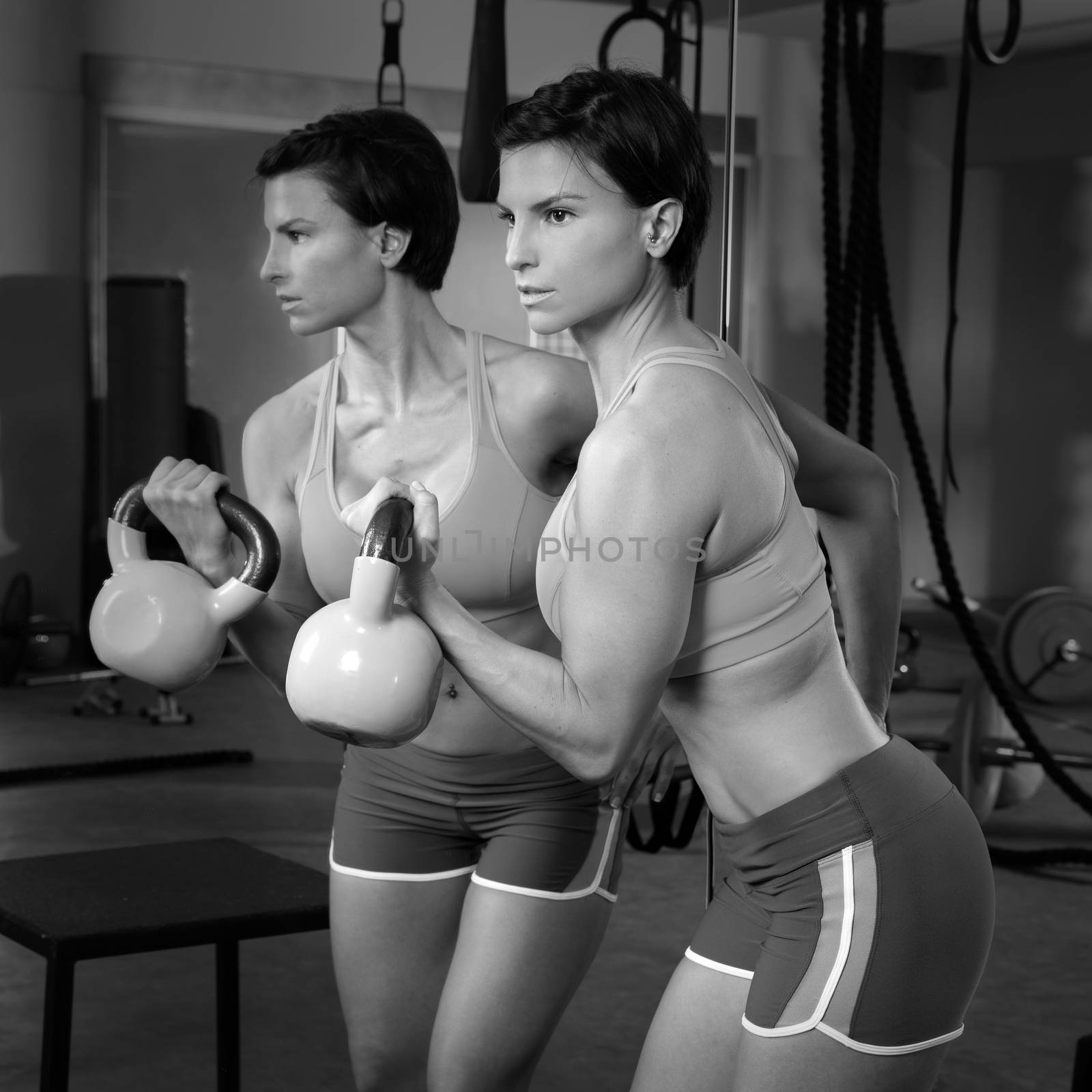 Crossfit fitness weight lifting Kettlebell woman at mirror workout exercise at gym