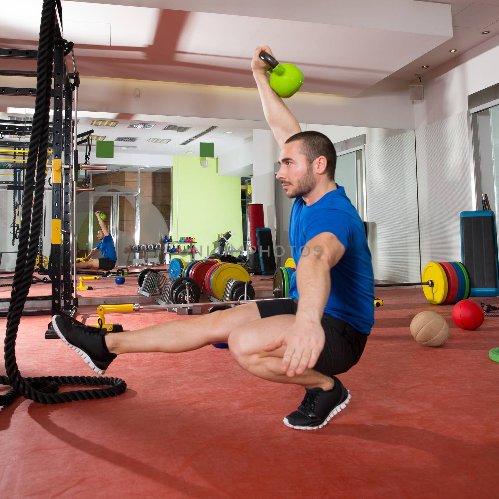 Crossfit fitness man balance Kettlebells with one leg by lunamarina