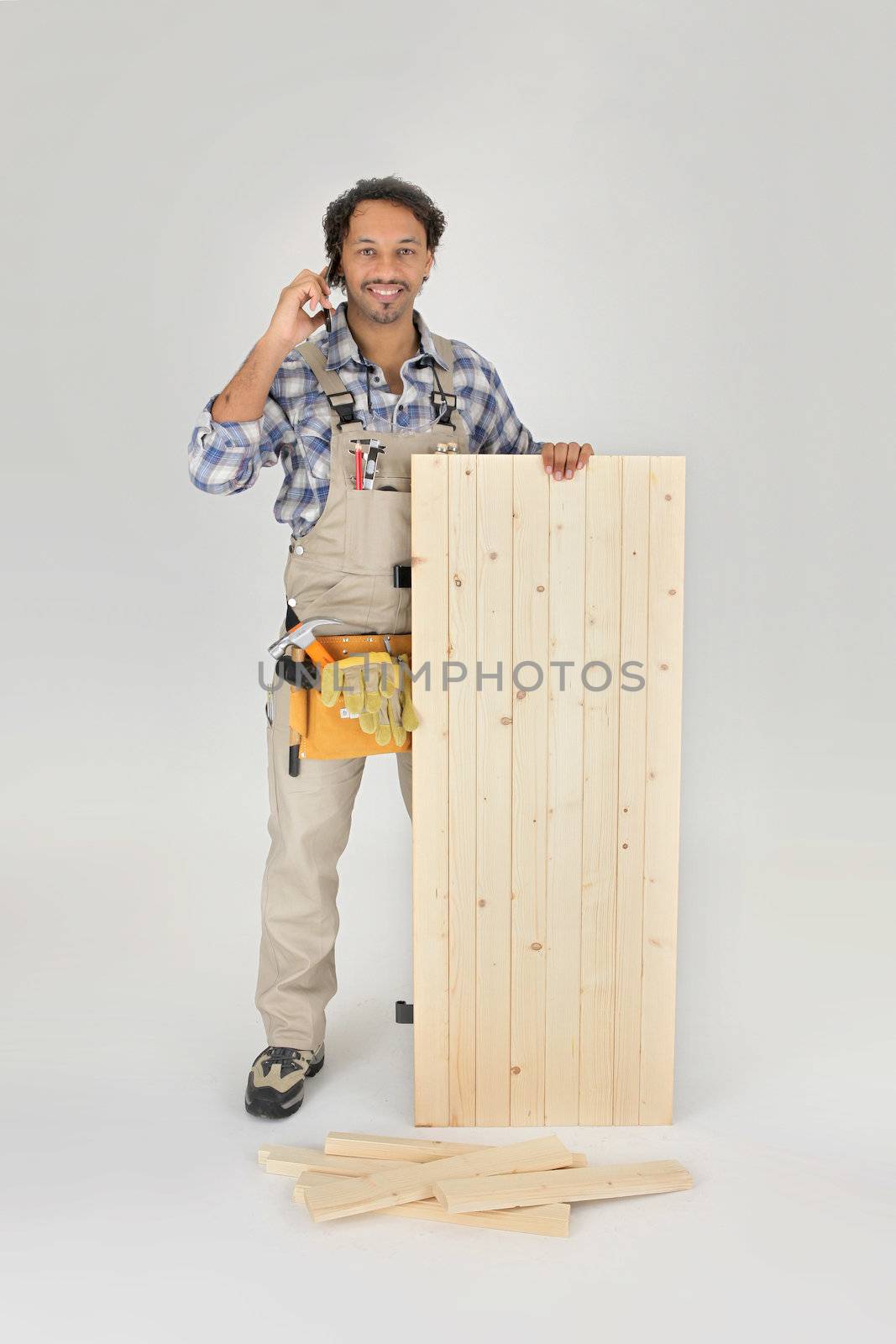 Carpenter stood with wooden door by phovoir