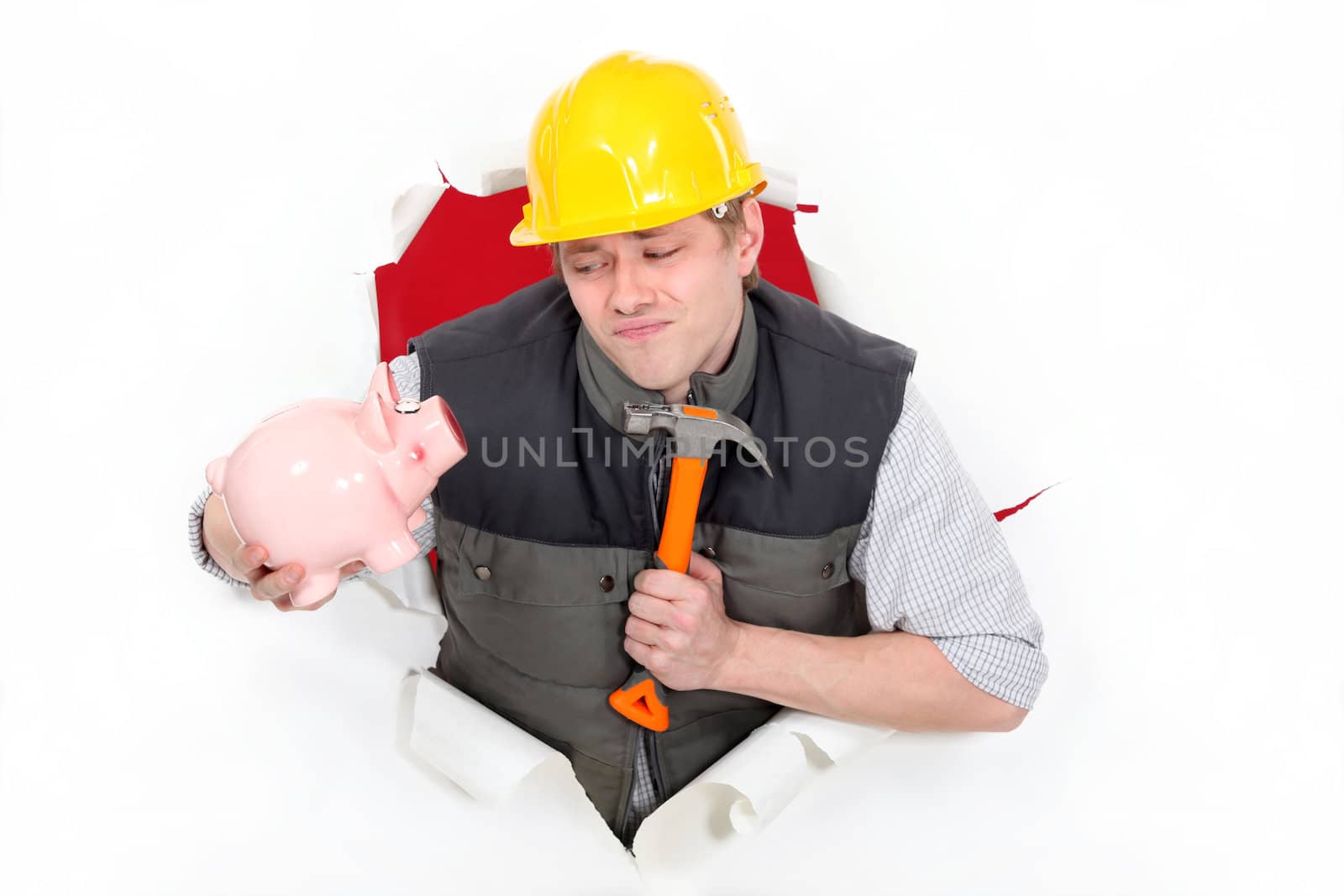 Laborer holding hammer and piggy bank by phovoir