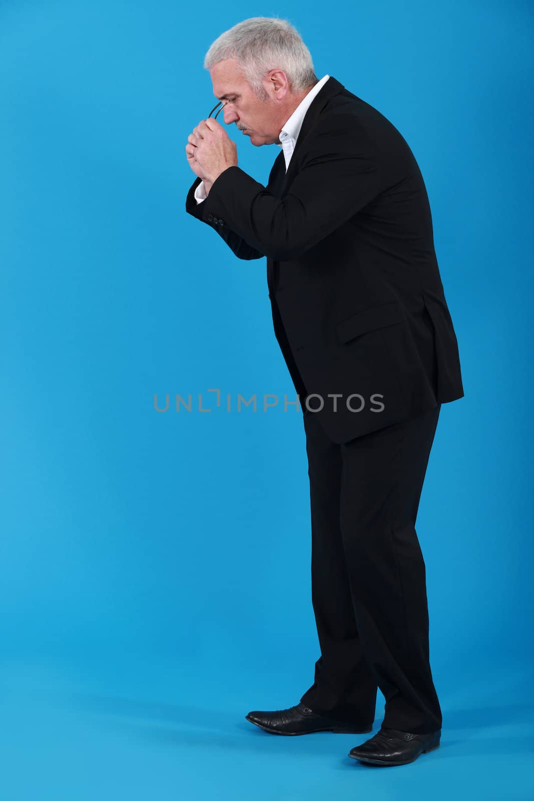 Businessman putting his eyeglasses on to look for an object