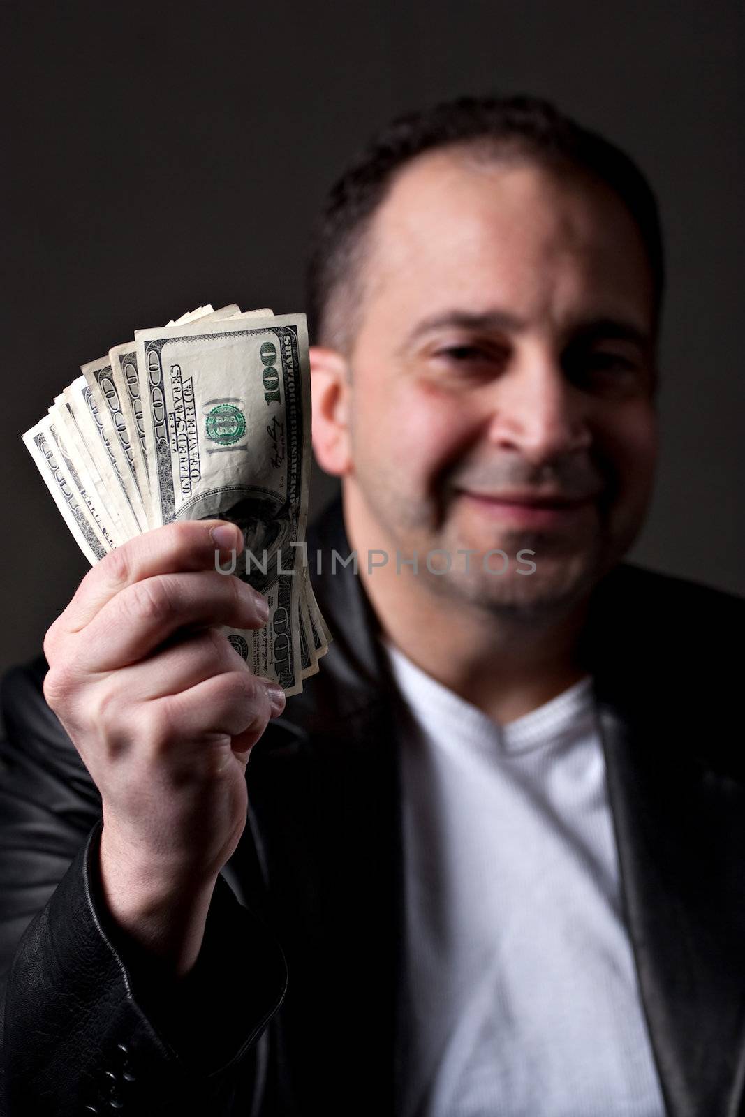 A happy man holds a handful of green American money with selective color.