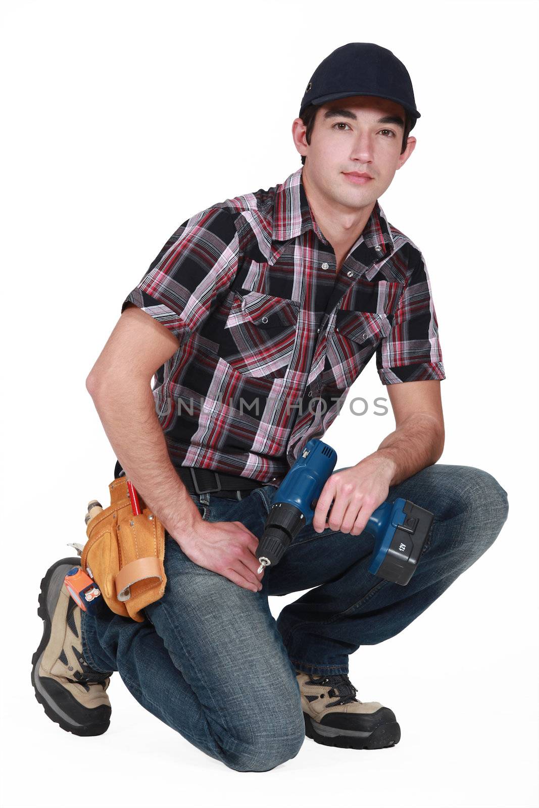 Young tradesman holding a rechargeable screwdriver by phovoir