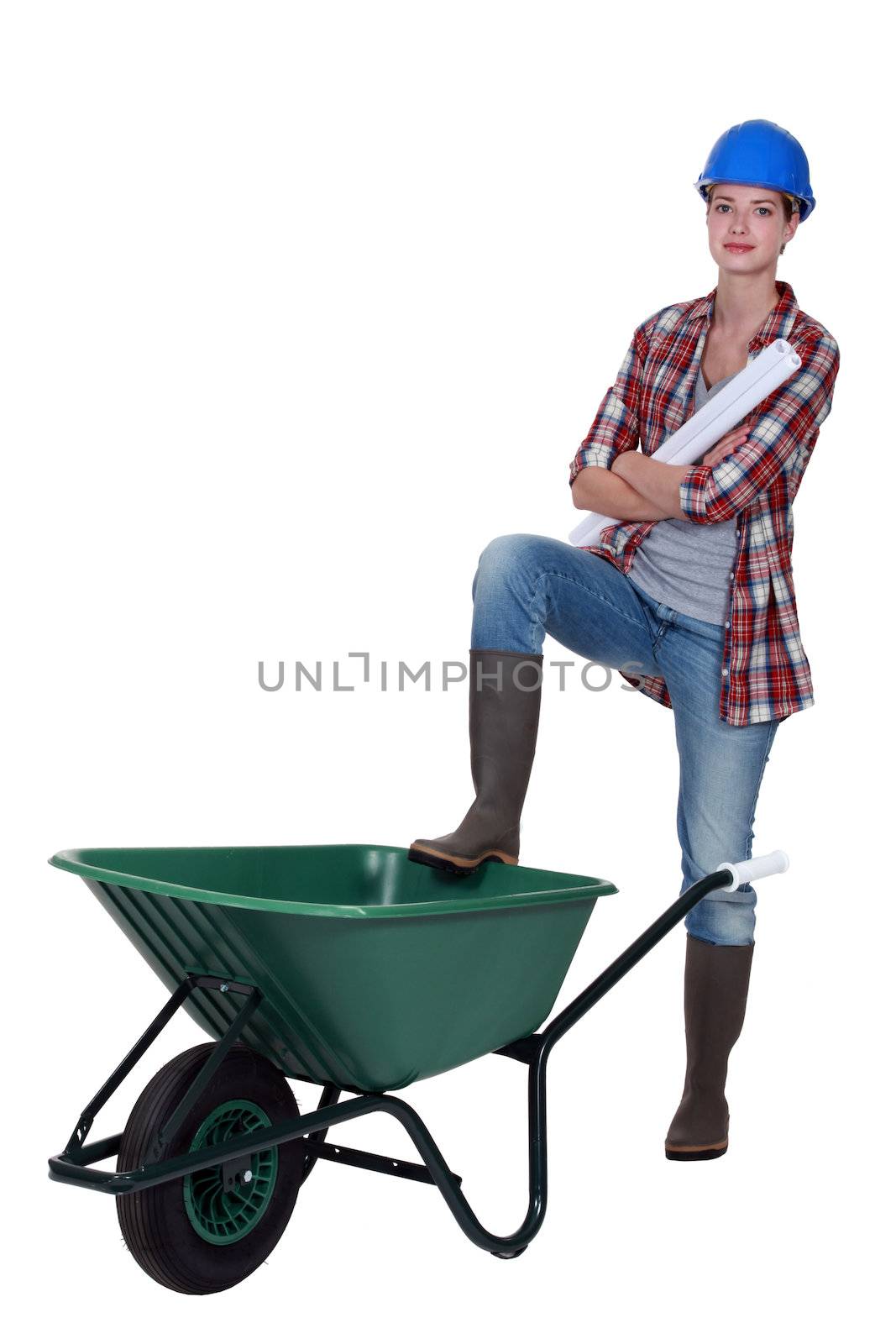 Tradeswoman with her foot propped on a wheelbarrow