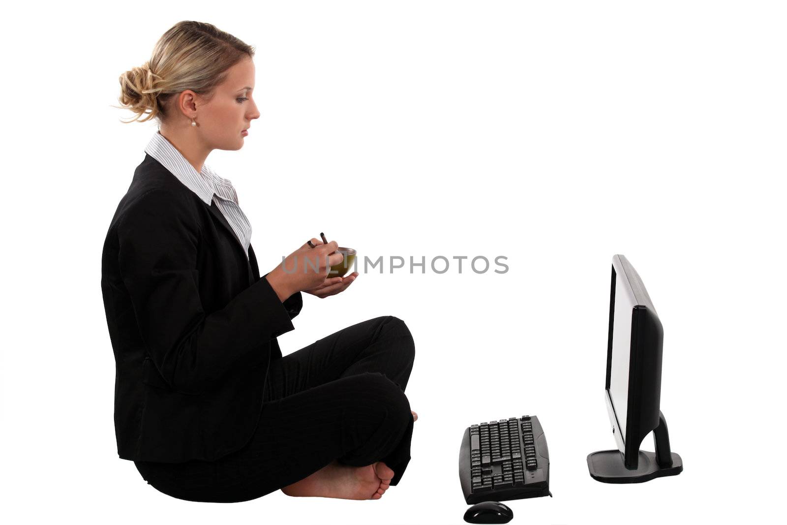 Blond businesswoman sat cross-legged in front of laptop by phovoir