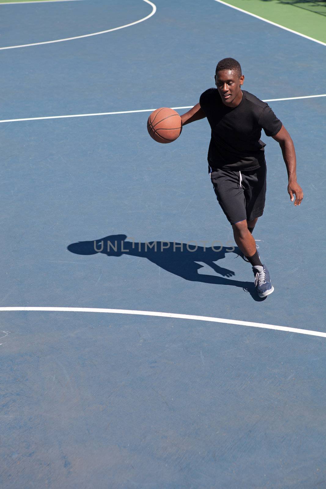 A sweaty young basketball player dribbling down the court demonstrating his ball handling skills.