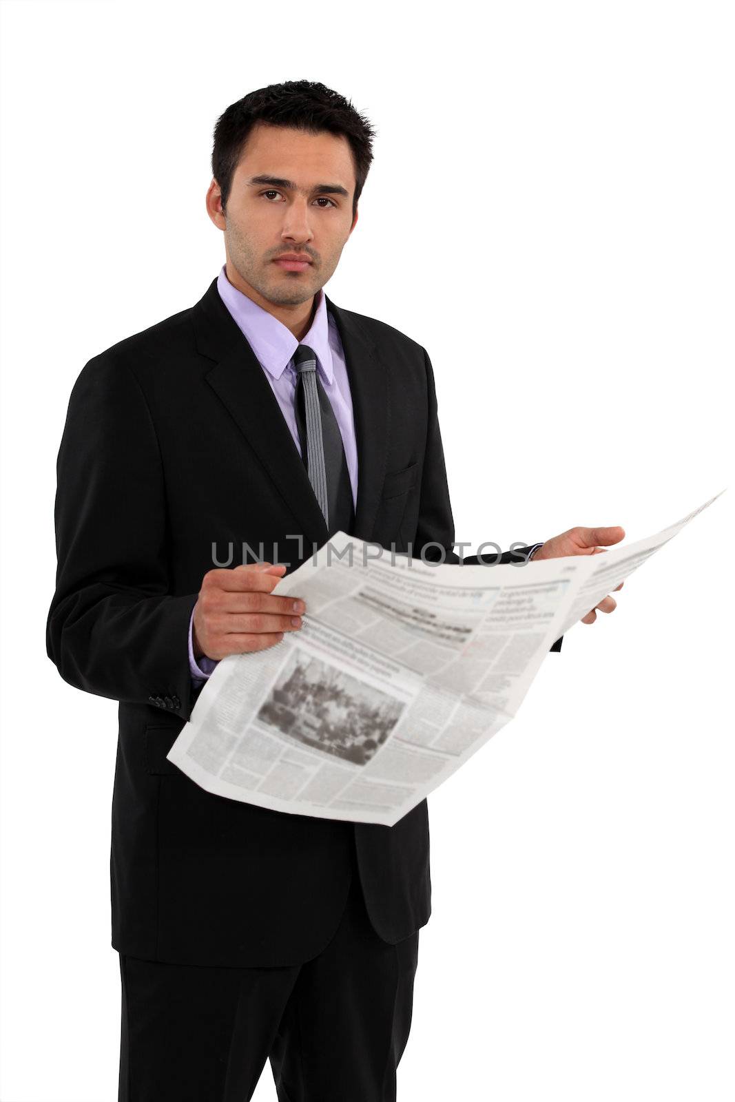 Businessman stood reading the daily newspaper by phovoir