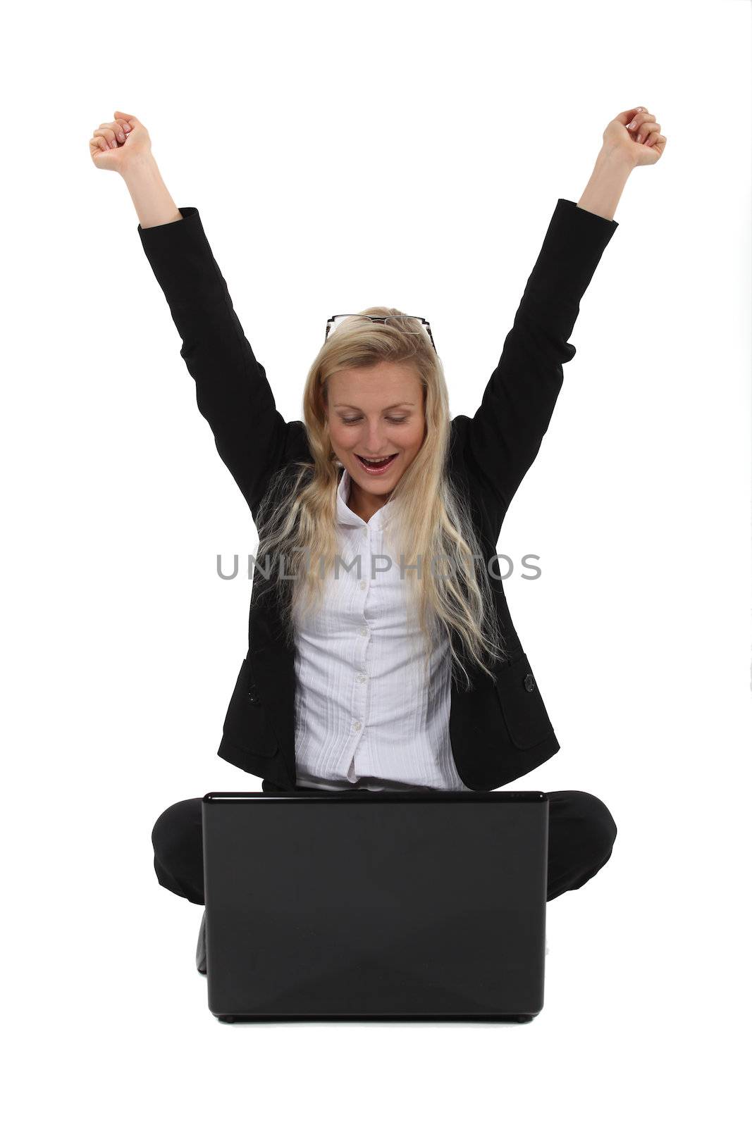 Excited businesswoman sat on the floor with laptop by phovoir