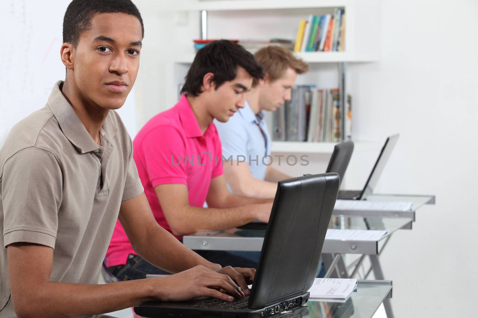 Young men working on their assignments in a computer lab by phovoir