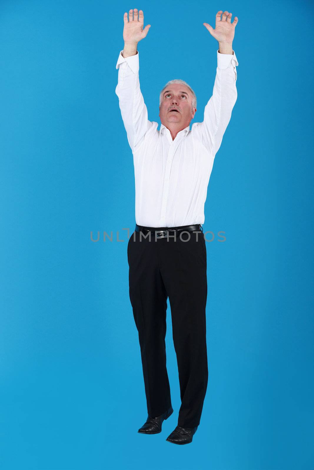 Grey haired businessman reaching into the air