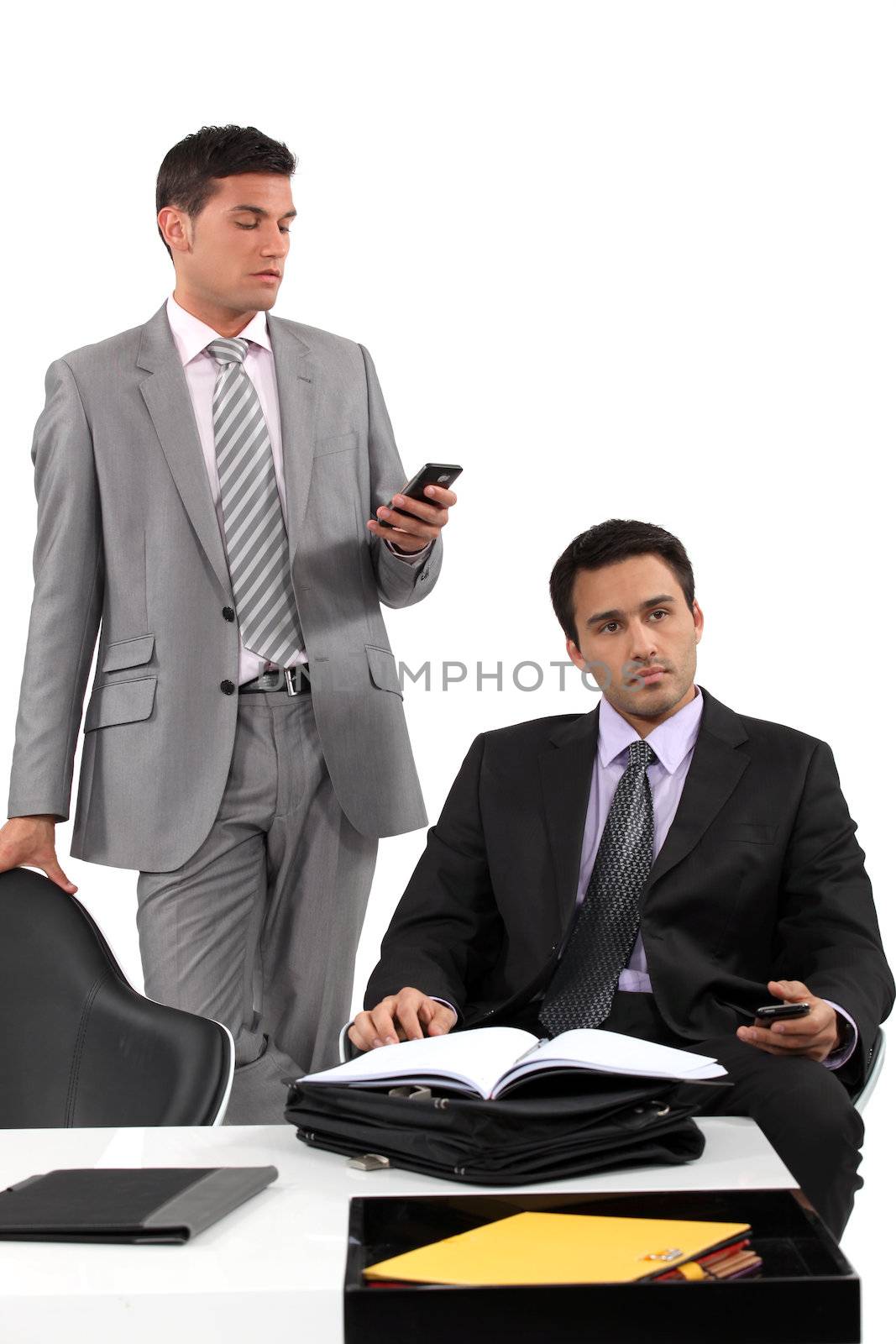 two businessmen sending messages on their cells