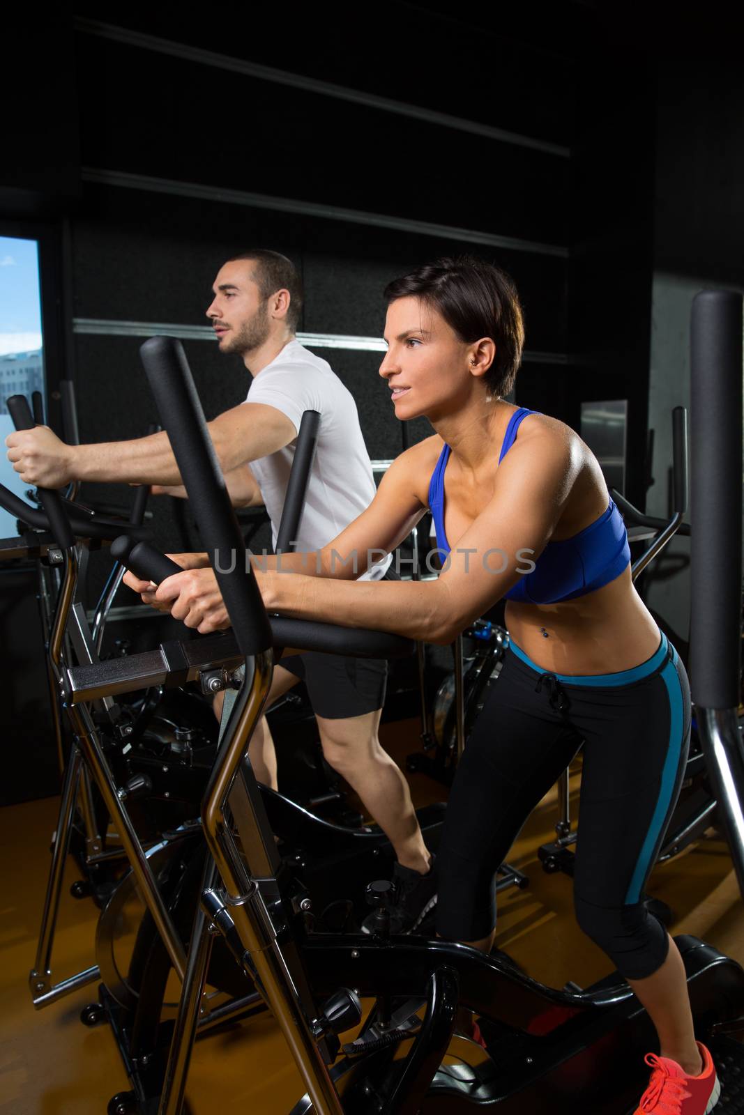 elliptical walker trainer man and woman at black gym training aerobics exercise