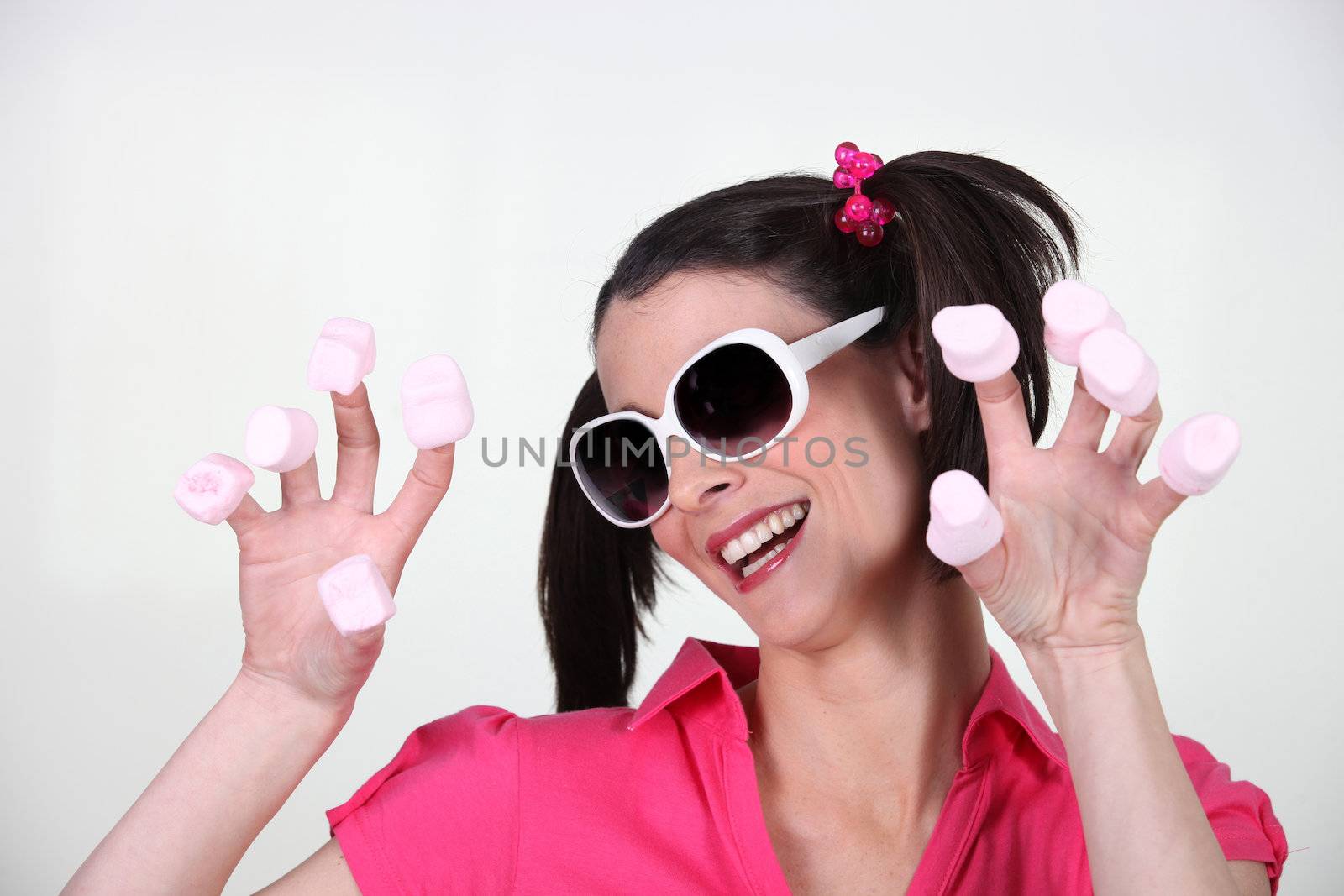Woman with marshmallows on fingers by phovoir