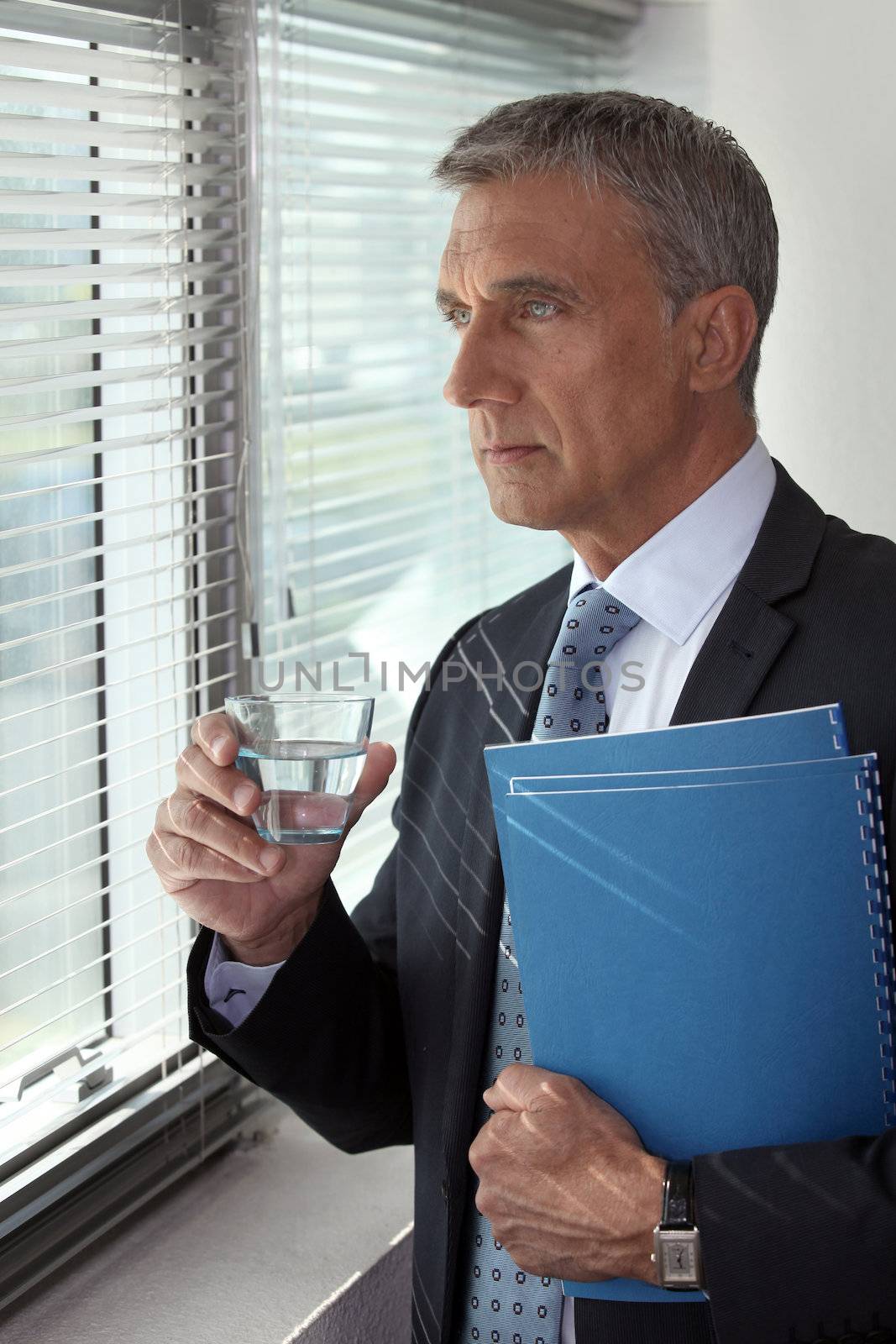 Businessman looking through his office window by phovoir