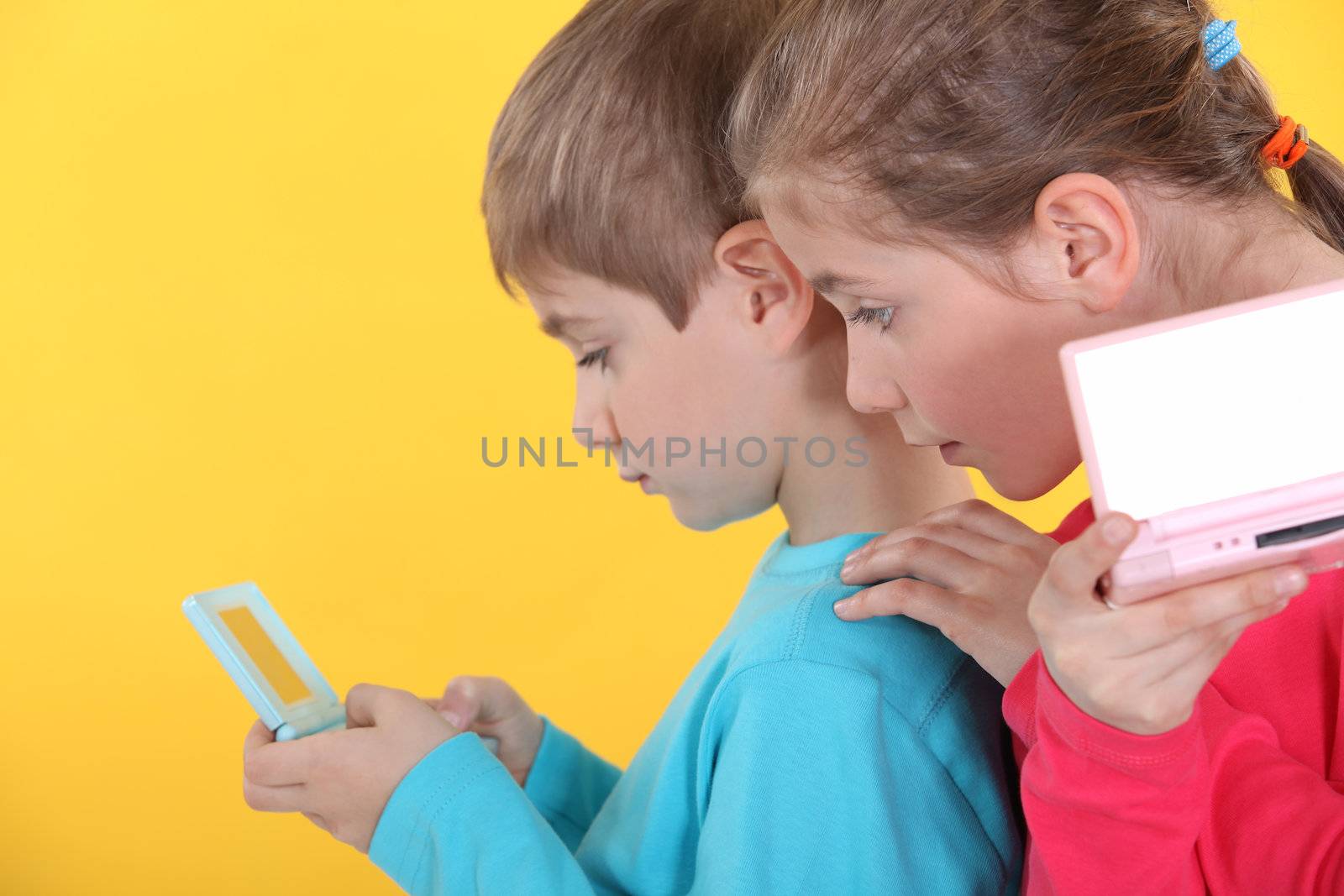 Children playing handheld video games by phovoir