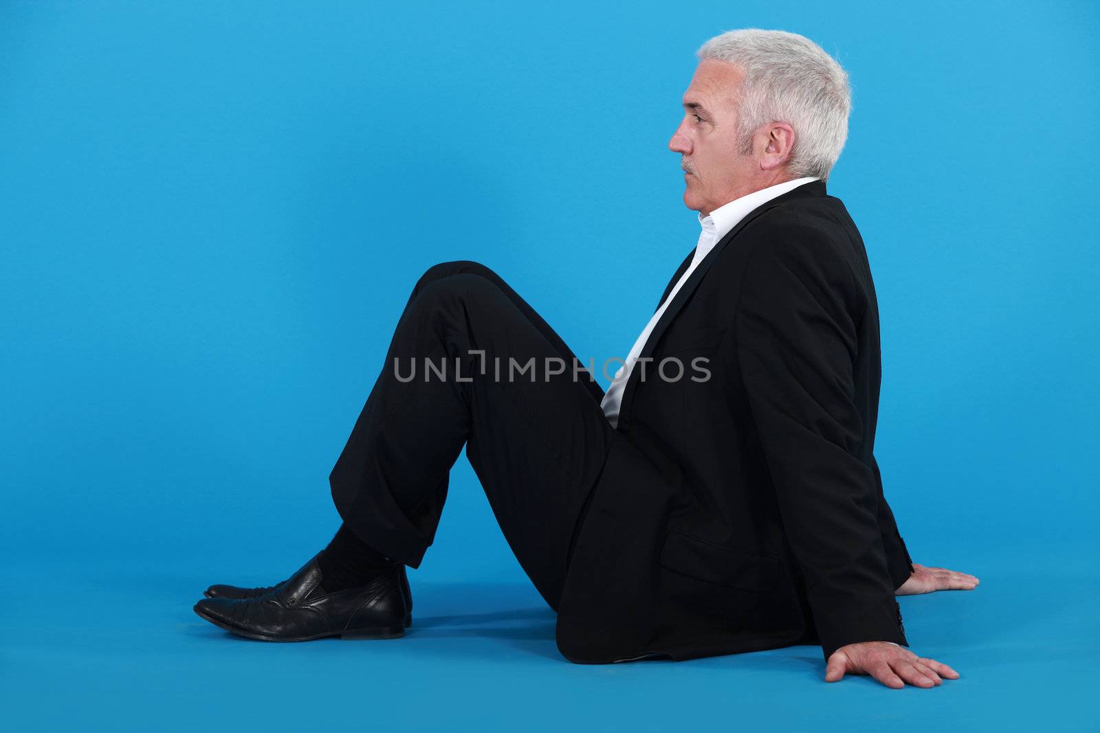 Elderly man sitting on the floor