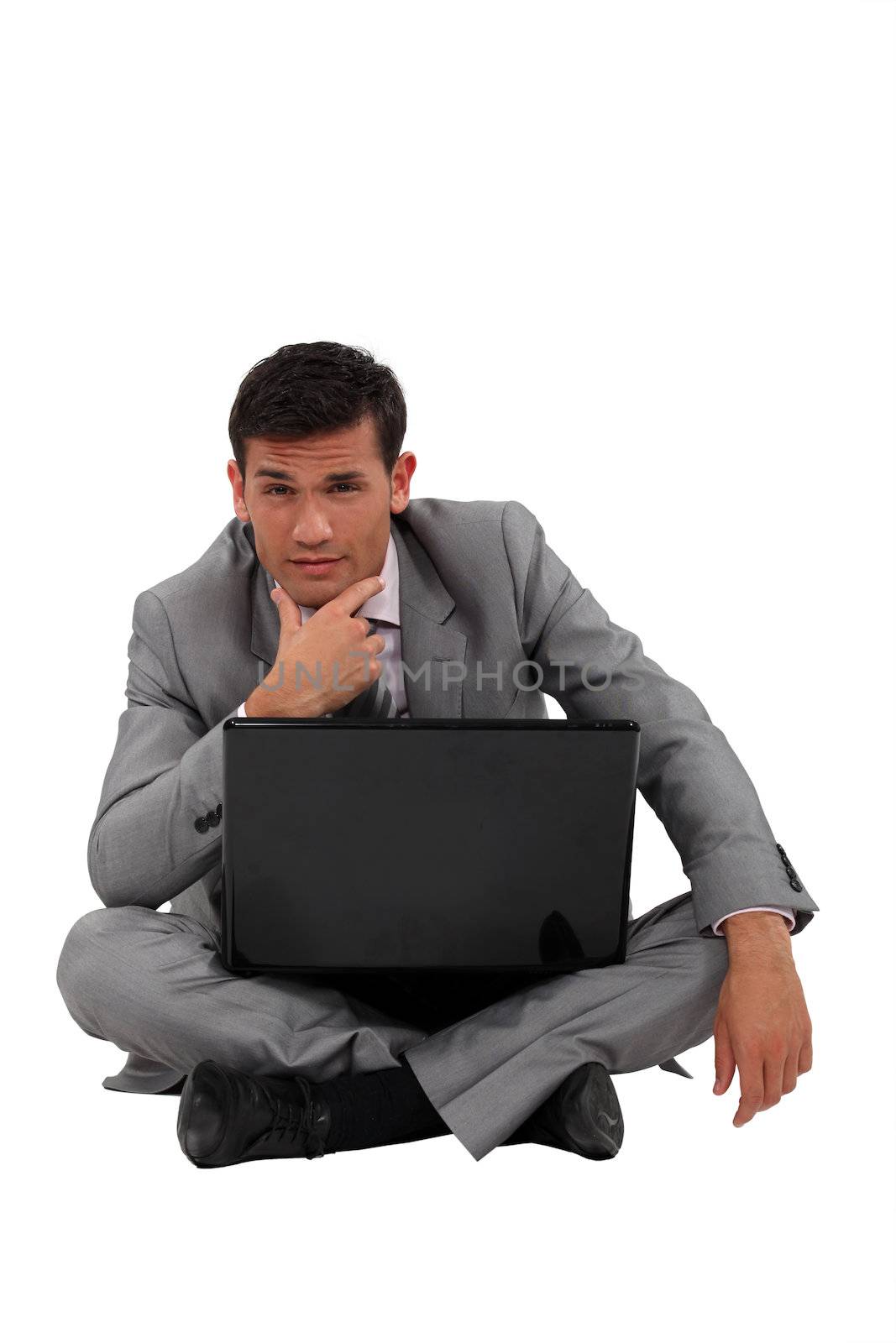 Pensive businessman sat on floor with laptop