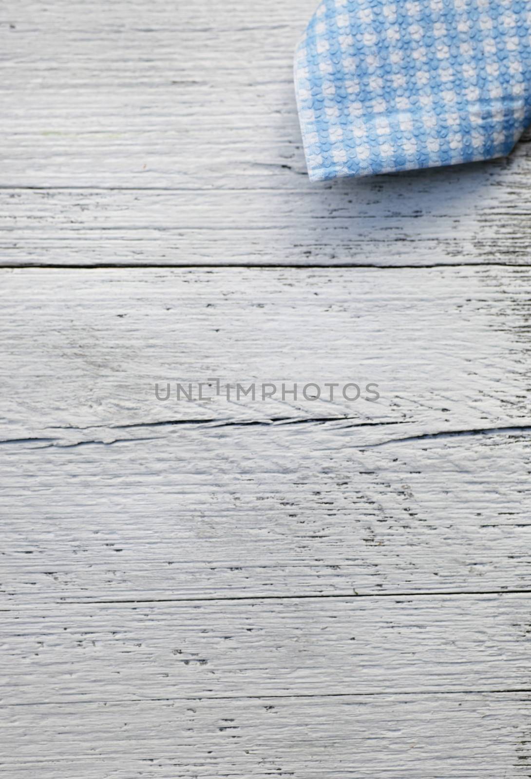 Rustic country background with a fresh blue and white checked napkin arranged in the corner of a white painted wooden background with cracked rough planks with copyspace