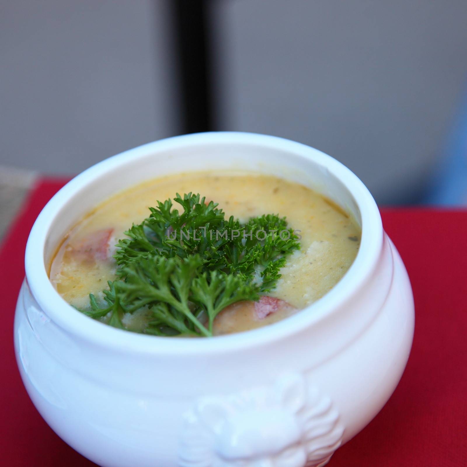 Bowl of hot creamy soup garnished with parsley on a table served as a starter or appetizer to a winter meal