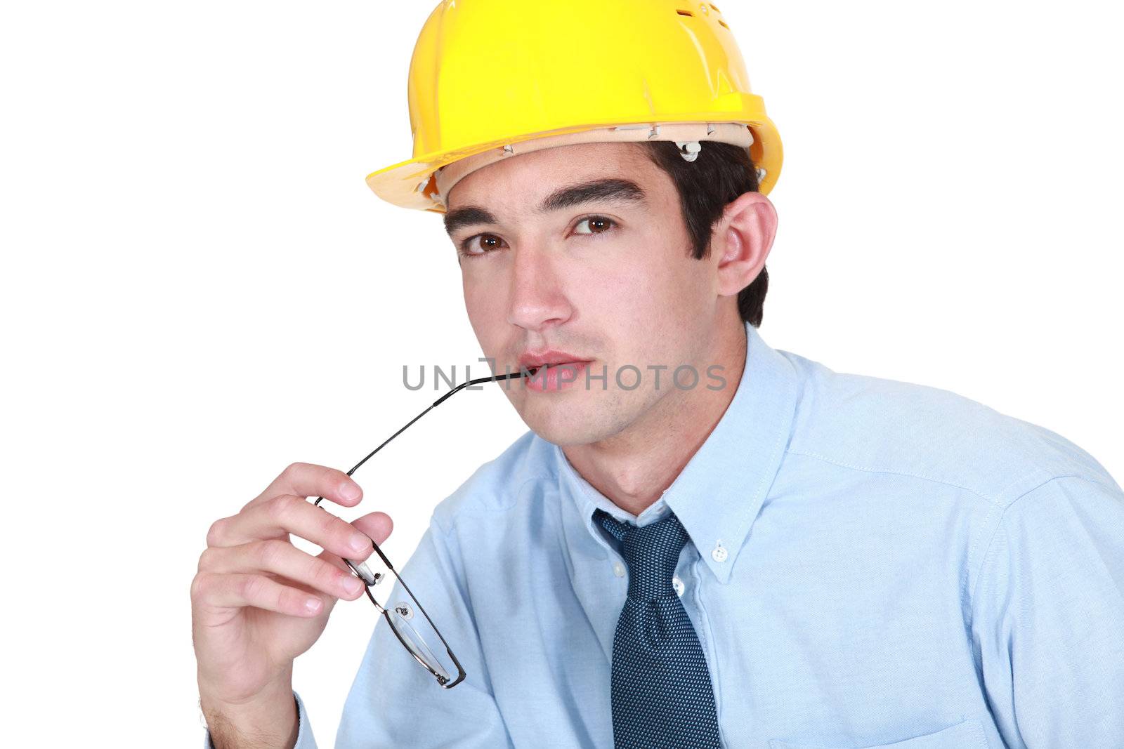 Pensive architect holding glasses to mouth by phovoir