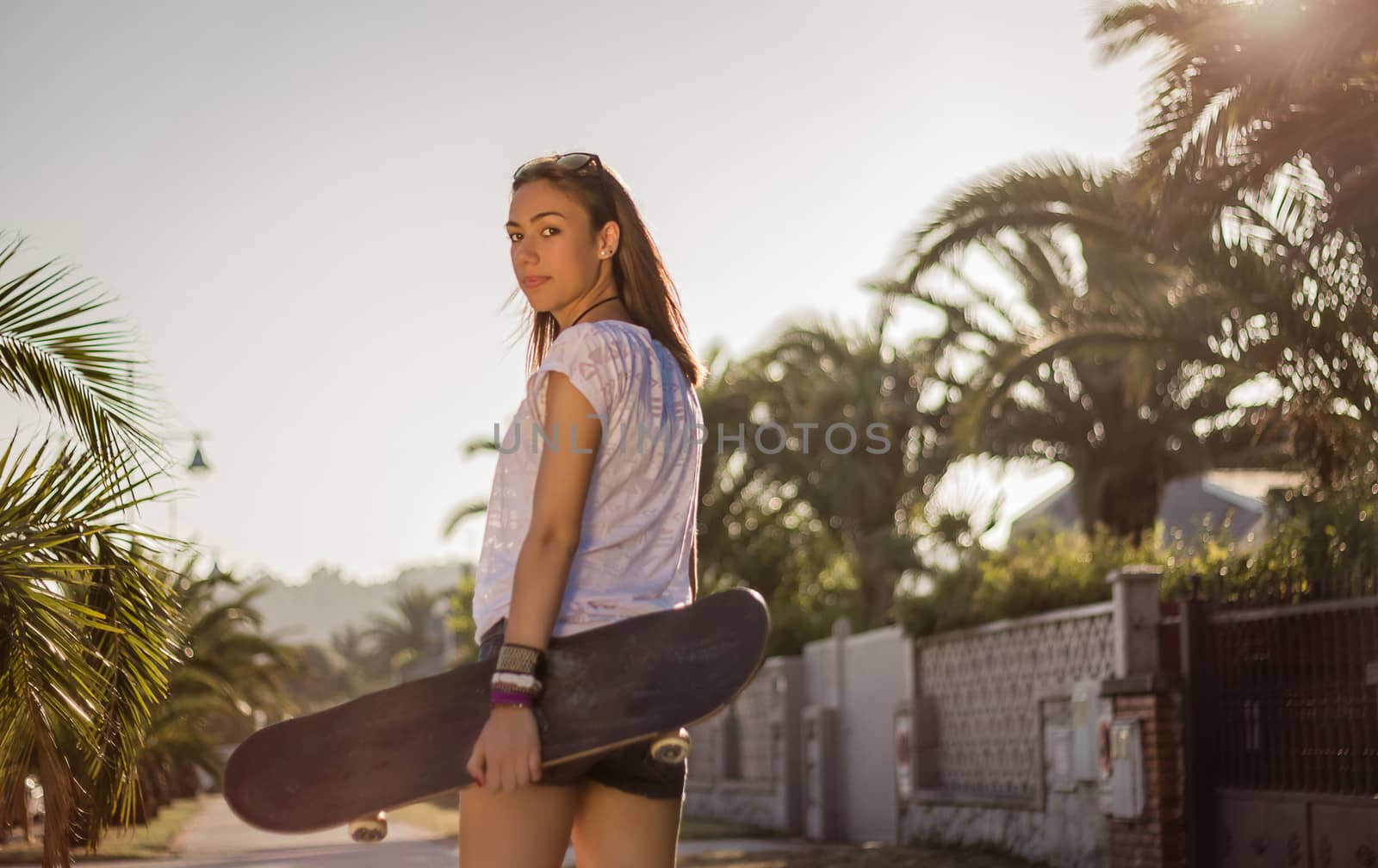 Beautiful young girl with a skateboard outdoor on summer
