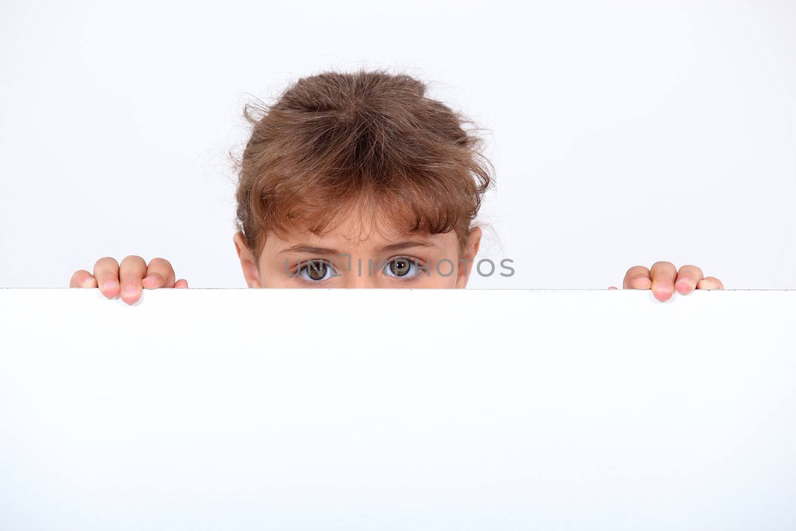 Girl peeking above a board by phovoir