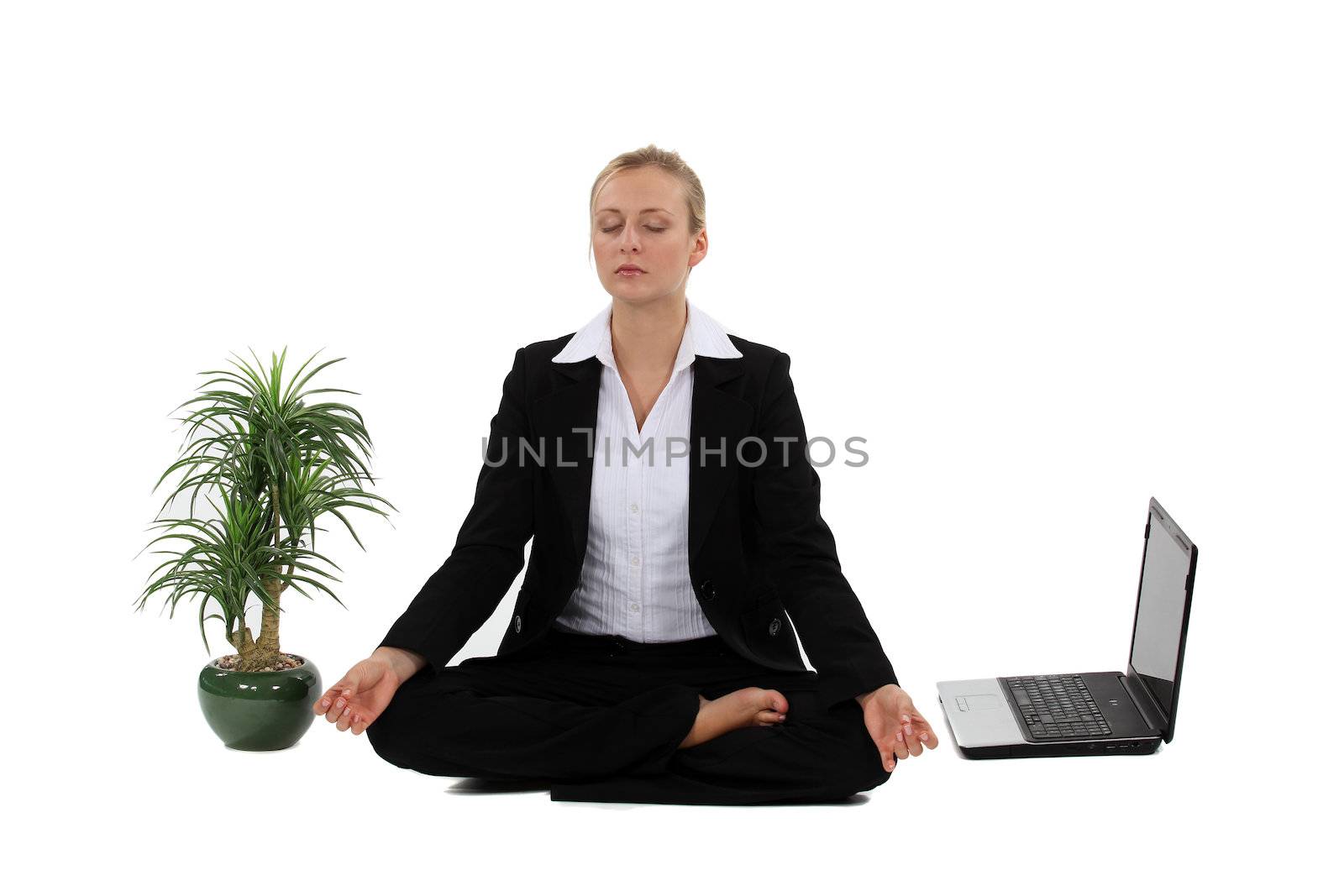 Businesswoman meditating next to her laptop by phovoir