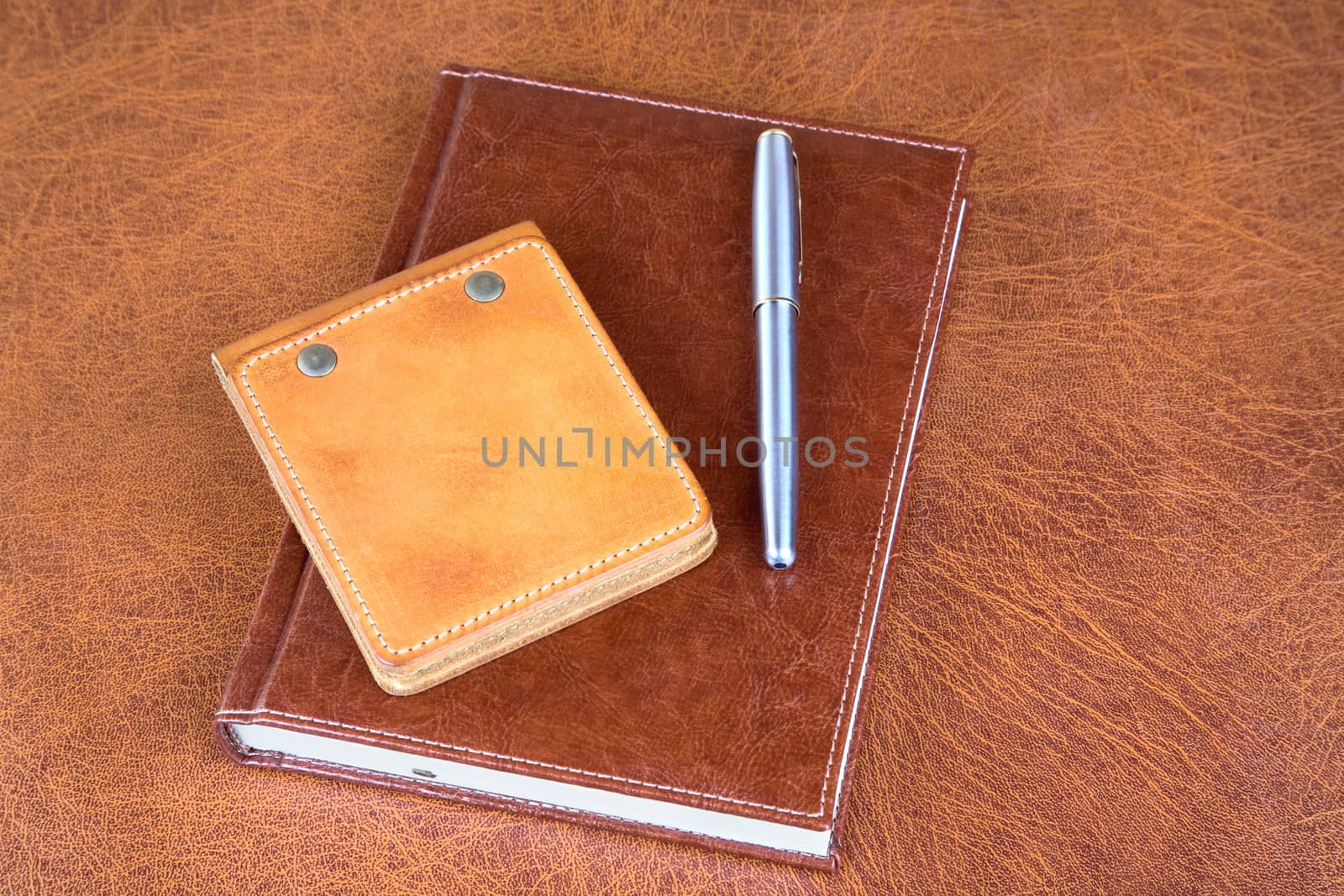 Leather organizers and fountain pen on a textural background