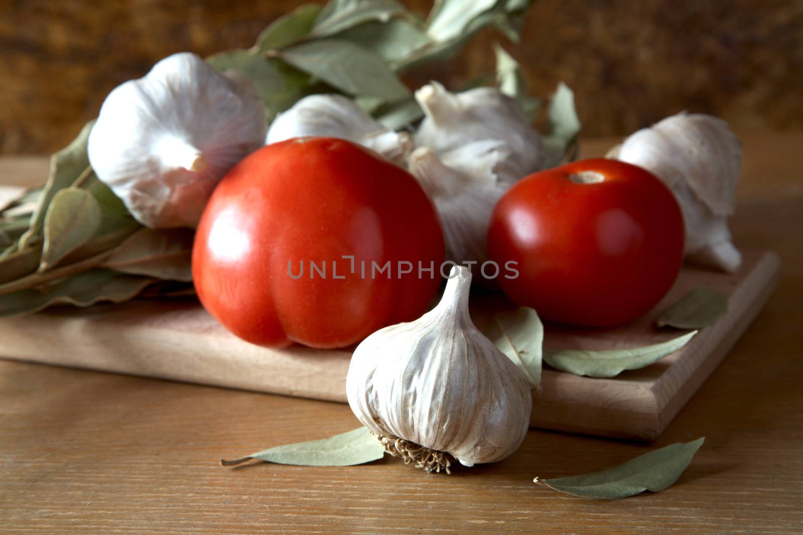 Tomatoes garlic and bay leaf branches on a kitchen table