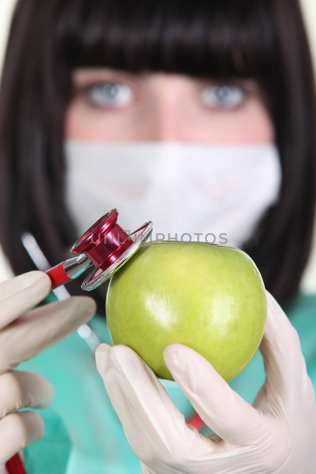 Medic using a stethoscope on an apple by phovoir