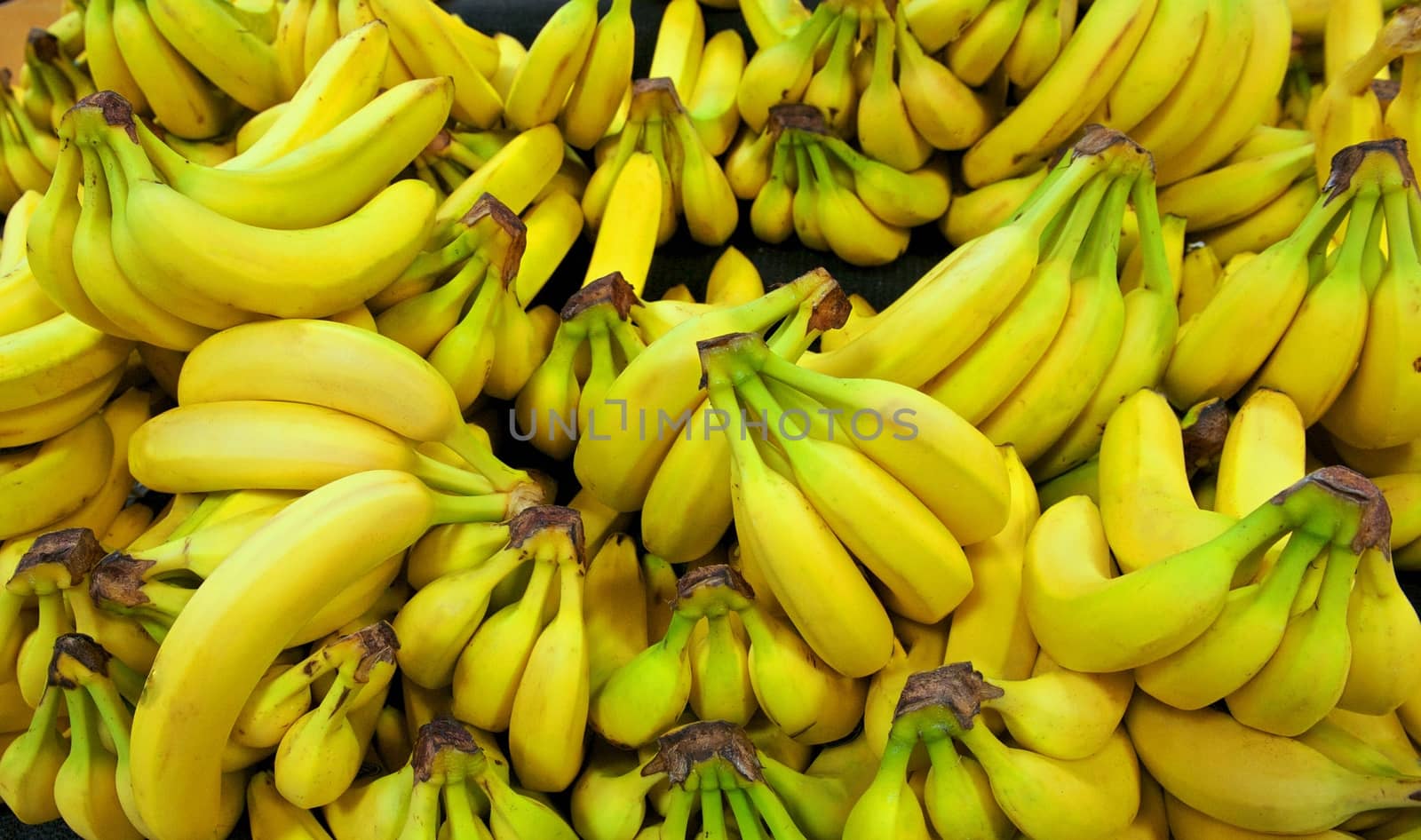 Yellow and green bananas are arranged in a pile in a grocery store