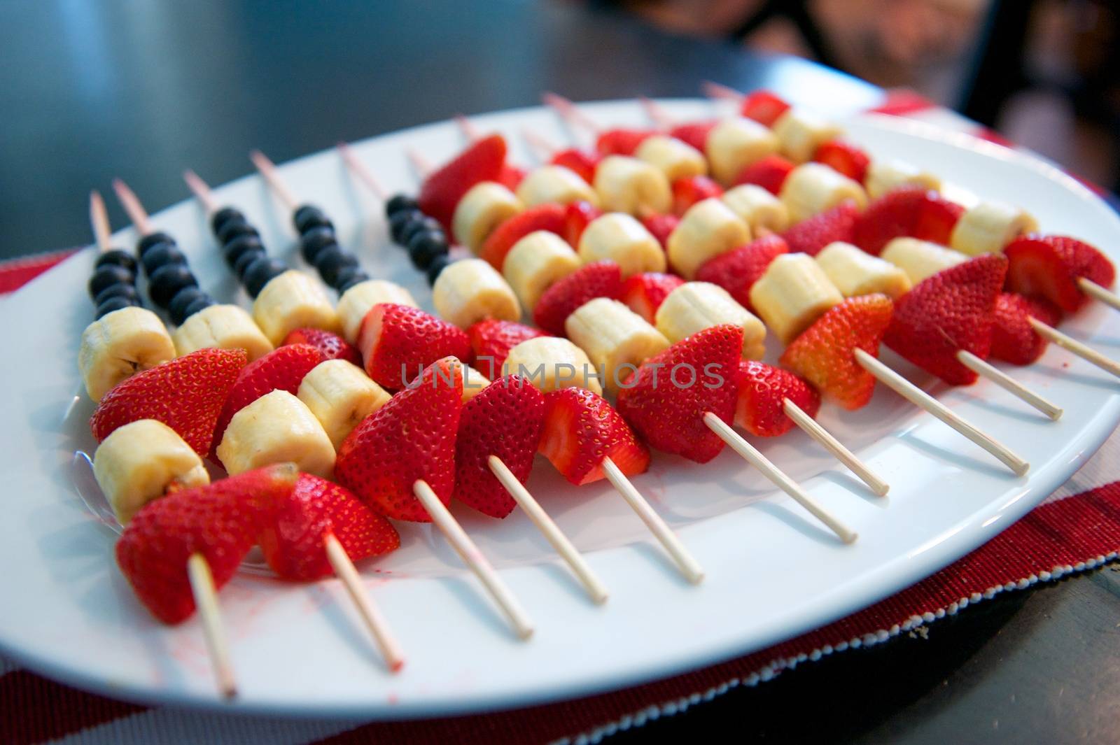 USA flag made entirely of fresh fruit and skewers on a white plate
