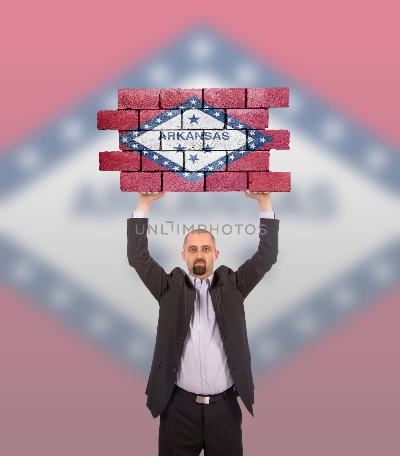 Businessman holding a large piece of a brick wall, flag of Arkansas, isolated on national flag