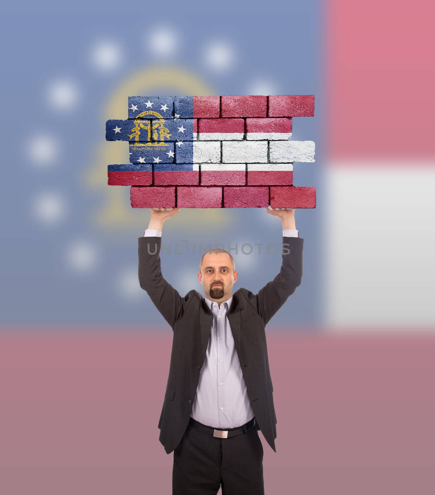 Businessman holding a large piece of a brick wall, flag of Georgia, isolated on national flag