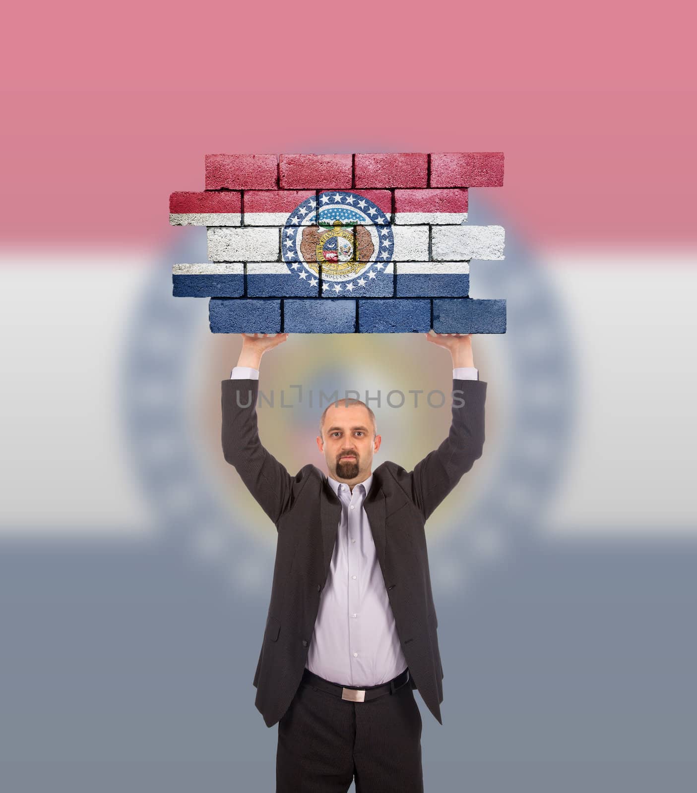 Businessman holding a large piece of a brick wall, flag of Missouri, isolated on national flag