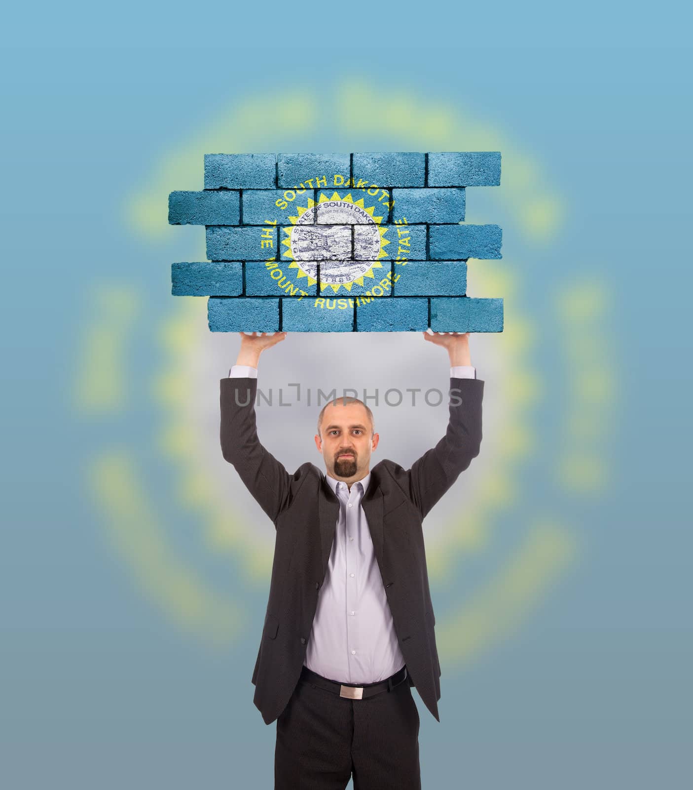 Businessman holding a large piece of a brick wall, flag of South Dakota, isolated on national flag