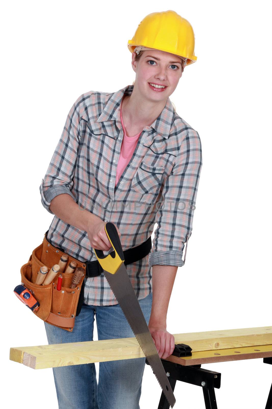 young female carpenter using saw by phovoir