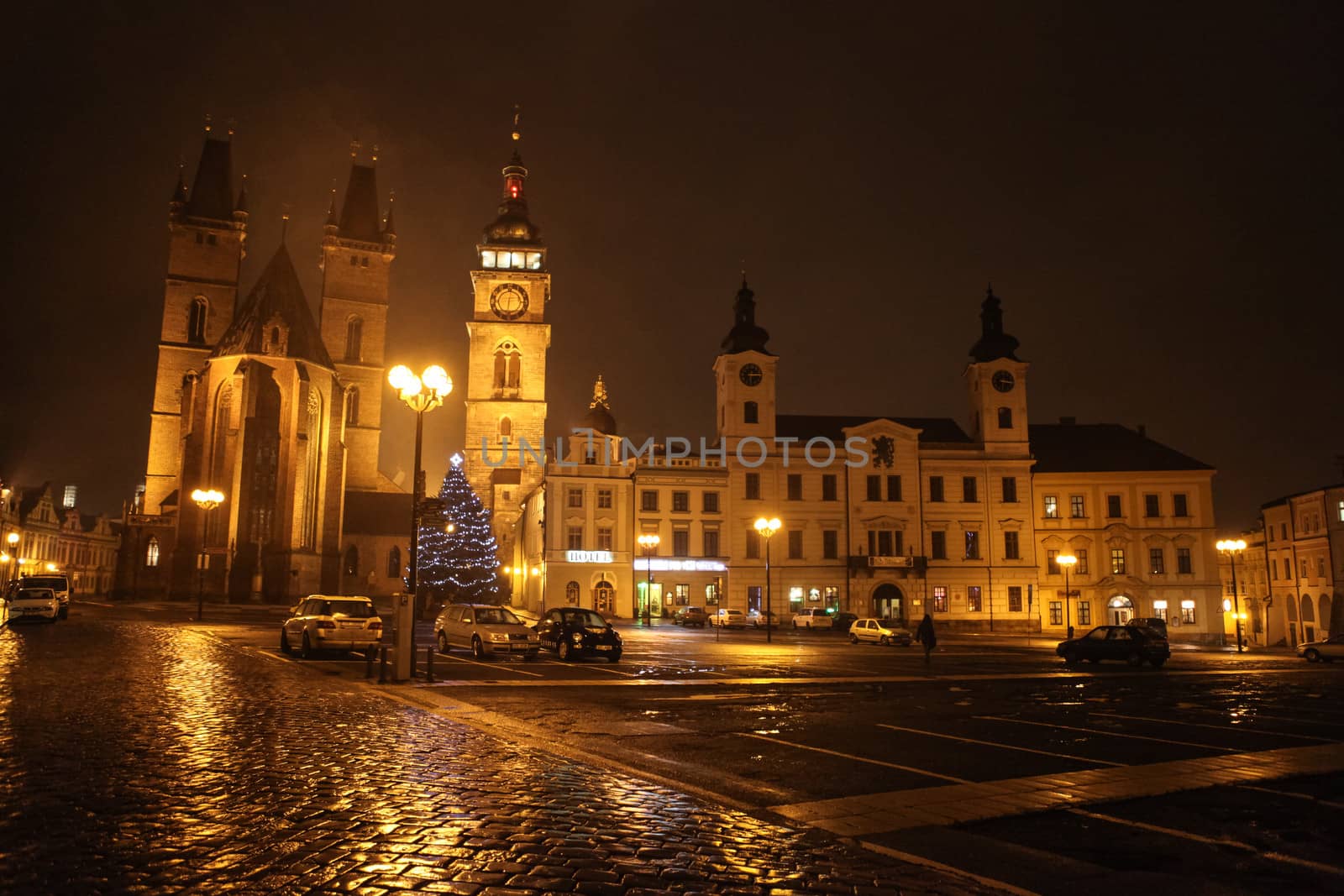 Hradec Králové, the Czech Republic - January 03, 2013: View at the Velké náměstí (Great Square), main old town square in the Czech Republic city of Hradec Králové at night, with illuminated 14th Century Cathedral of the Holy Spirit (on the left), Renaissance campanile White Tower (the highest building in the middle), the Town Hall and other surrounding buildings. One unrecognizable person visible in the picture.