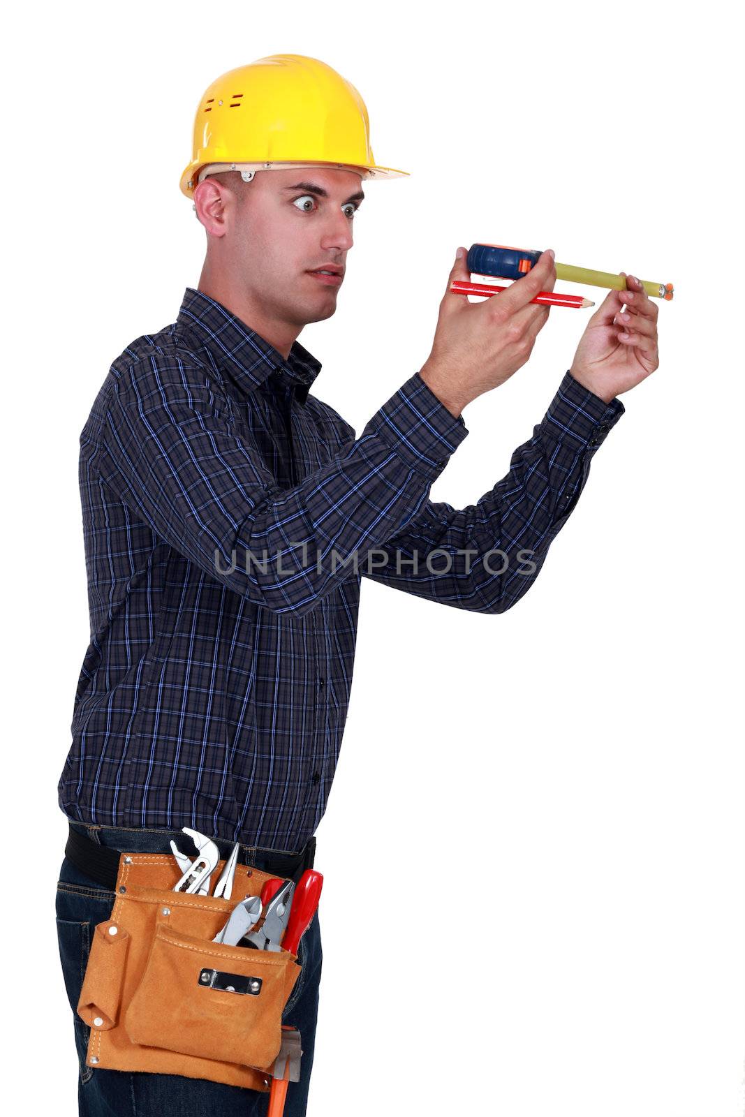 Man looking at his measuring tape surprisingly by phovoir