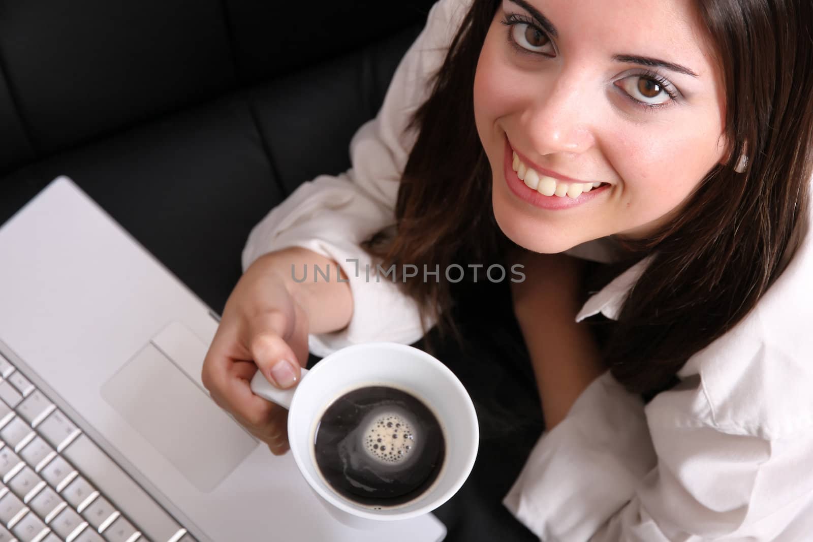 A young, hispanic adult girl with a Laptop and drinking coffee.
