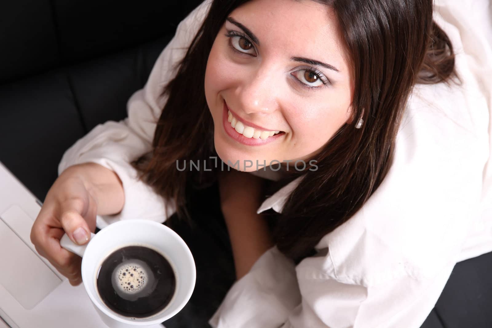 A young, hispanic adult girl with a Laptop and drinking coffee.
