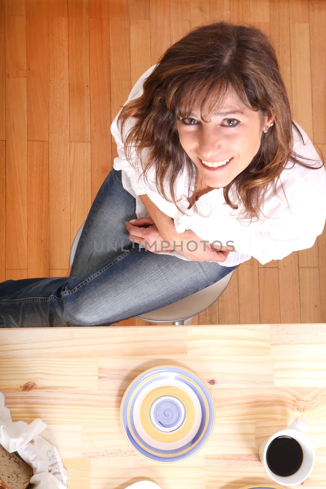 Portrait of a beautiful mature woman sitting in the kitchen. Focus on the Table.