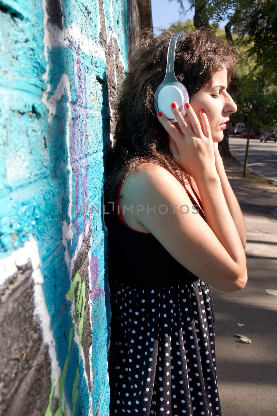 A vintage dressed girl listing to music in a urban environment.