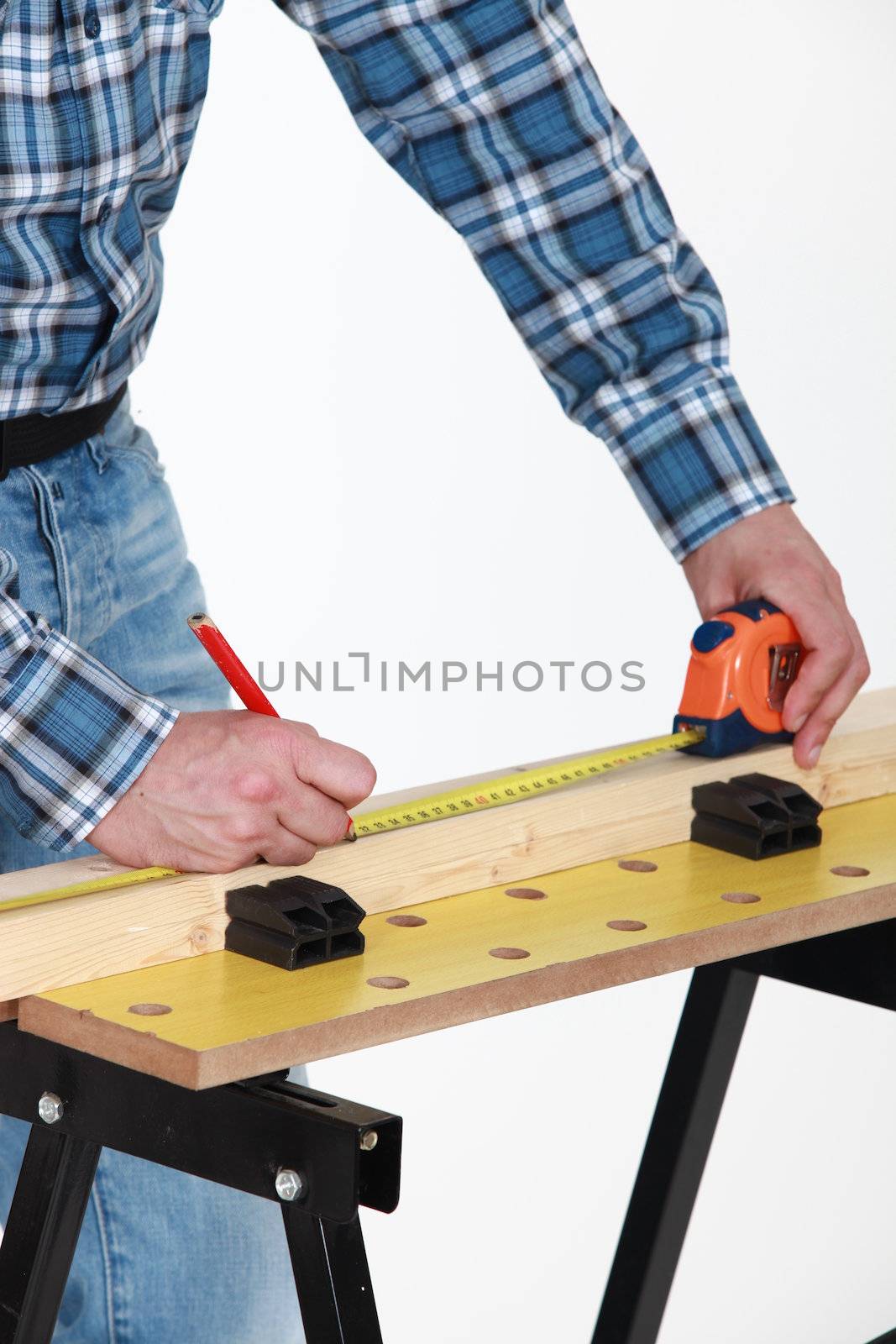 Carpenter measuring a plank by phovoir