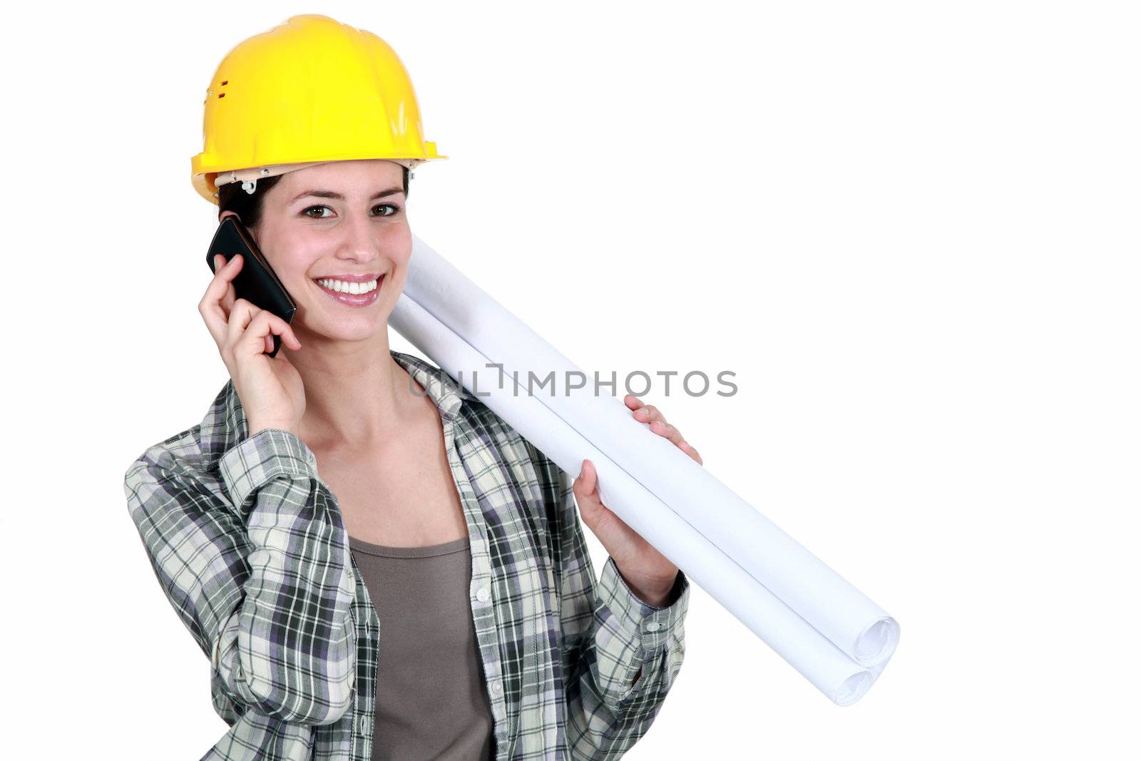 Female builder with plans and mobile telephone by phovoir