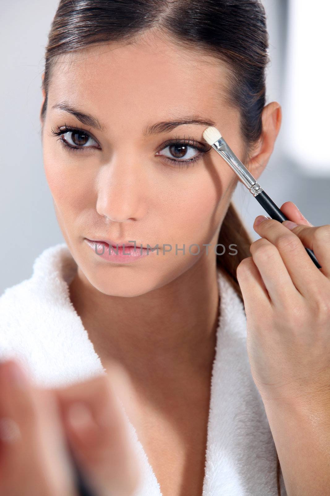 Woman applying eye make-up by phovoir